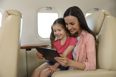 Mother with daughter using tablet in airplane during flight