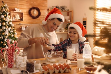Happy father and his son making dough for Christmas cookies at home