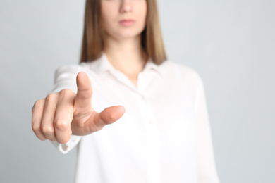 Photo of Young woman against light grey background, focus on hand