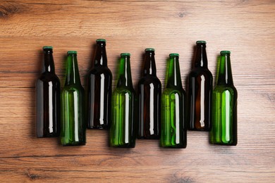 Photo of Bottles of tasty beer on wooden table, flat lay