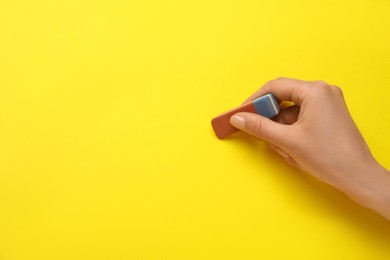 Woman erasing something on yellow background, closeup. Space for text