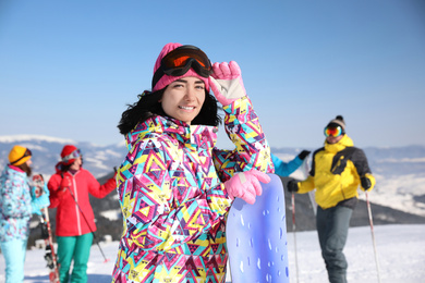Young woman with snowboard at ski resort. Winter vacation