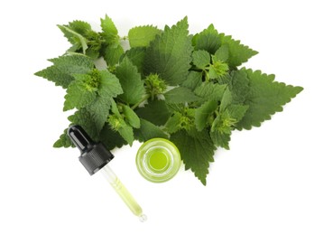 Glass bottle of nettle oil with dropper and leaves isolated on white, top view