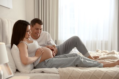 Young pregnant woman with her husband in bedroom