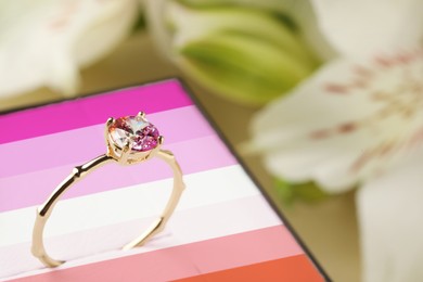 Box in color of lesbian flag and beautiful engagement ring against blurred background, closeup
