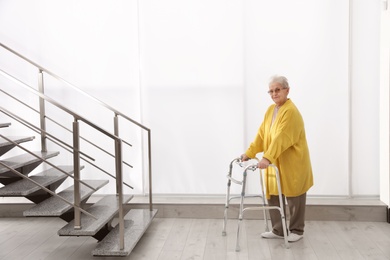 Photo of Senior woman with walker near stairs in hospital