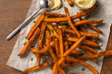 Delicious sweet potato fries and sauce on wooden table, top view