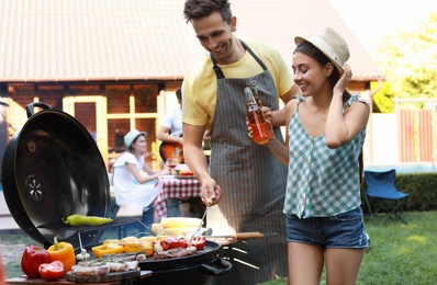 Young man and woman near barbecue grill outdoors