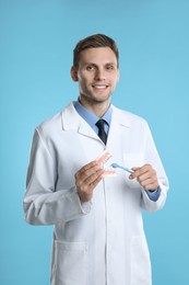 Dentist with jaws model and toothbrush on light blue background. Oral care demonstration
