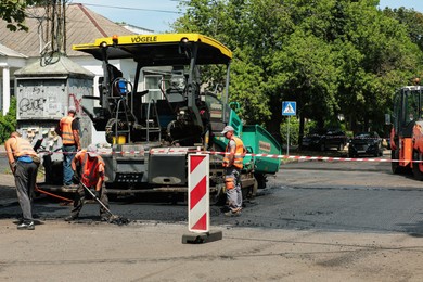 MYKOLAIV, UKRAINE - AUGUST 04, 2021: Workers with road repair machinery laying new asphalt