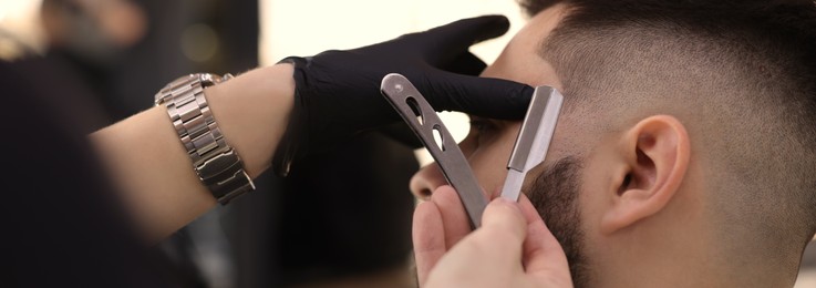 Professional hairdresser working with client in barbershop, closeup. Banner design