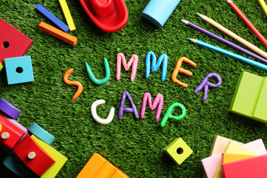 Photo of Flat lay composition with phrase SUMMER CAMP made of modelling clay on green grass