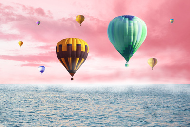 Dream world. Hot air balloons in pink sky with clouds over misty sea