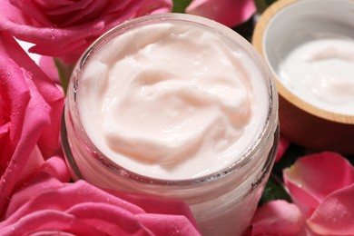Jar of face cream among beautiful roses, closeup