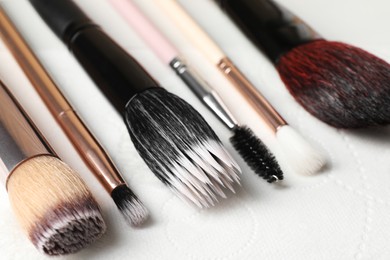 Photo of Set of different makeup brushes drying after cleaning on paper towel, closeup