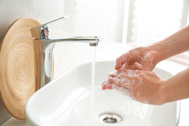 Woman washing hands indoors, closeup. Bathroom interior
