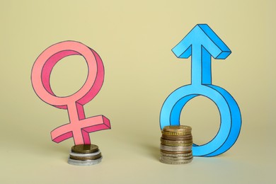 Photo of Gender pay gap. Male and female symbols near piles of coins on beige background