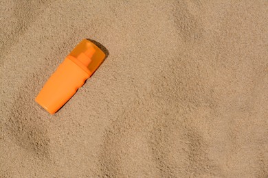 Bottle with sun protection spray on sandy beach, top view. Space for text