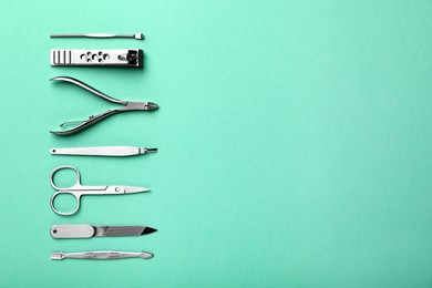 Photo of Set of manicure tools on turquoise background, flat lay. Space for text
