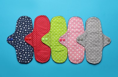 Many reusable cloth menstrual pads on light blue background, flat lay