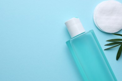 Micellar water and cotton pad on light blue background, flat lay. Space for text