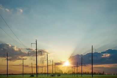 Telephone poles with cables in field under clear sky