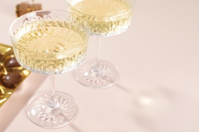 Photo of Glasses of expensive white wine on pink background, closeup. Space for text