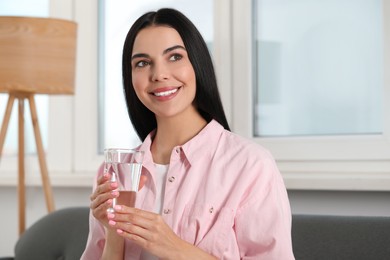 Young woman with glass of water indoors. Refreshing drink
