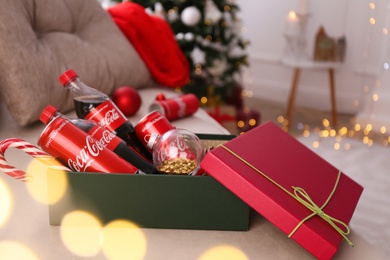 MYKOLAIV, UKRAINE - JANUARY 13, 2021: Coca-Cola bottles and cans, candy cane, Christmas decor in box indoors