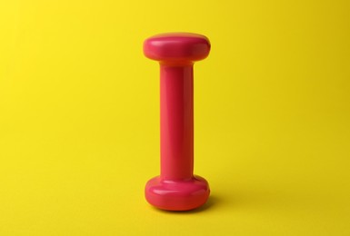 Stylish dumbbell for exercise on yellow background