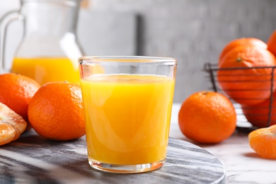 Glass of fresh tangerine juice and fruits on board