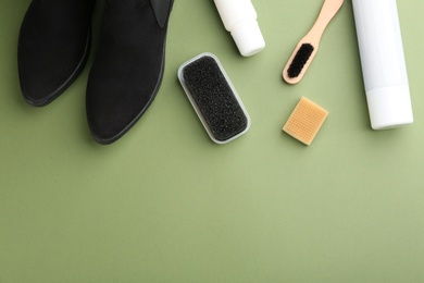 Stylish footwear with shoe care accessories on green background, flat lay. Space for text