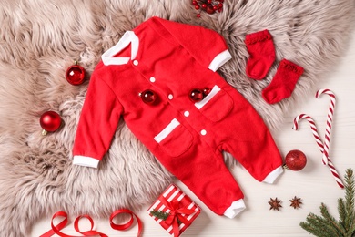 Flat lay composition with cute Christmas baby clothes on white wooden background
