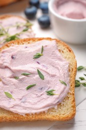 Tasty sandwiches with cream cheese and thyme on white wooden table, closeup