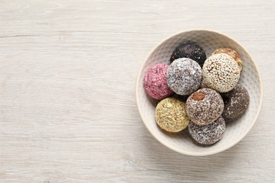Different delicious vegan candy balls on white wooden table, top view. Space for text
