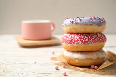 Delicious glazed donuts on white wooden table. Space for text