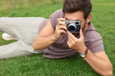 Photo of Man with camera taking photo on green grass. Interesting hobby