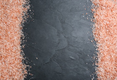 Frame of pink himalayan salt on black table, flat lay. Space for text