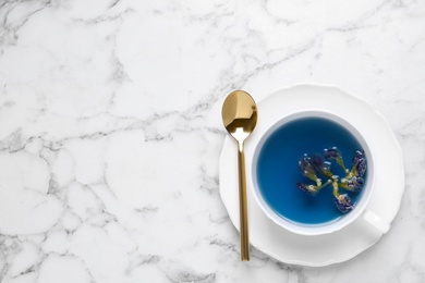 Organic blue Anchan in cup on white marble table, top view with space for text. Herbal tea