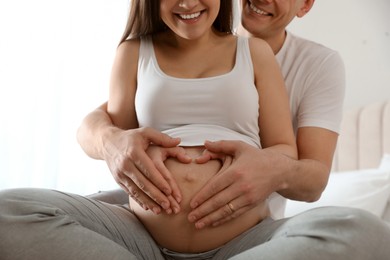 Photo of Young pregnant woman with her husband indoors, closeup