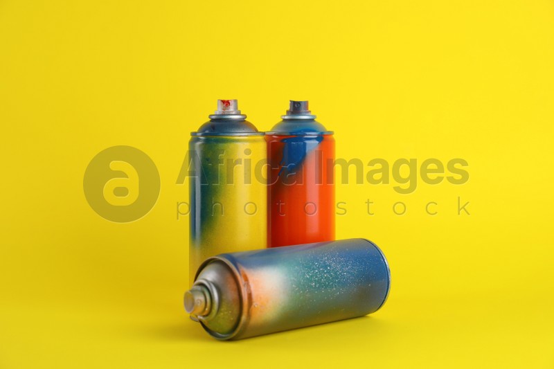 Photo of Used cans of spray paints on yellow background
