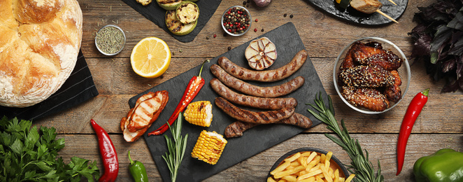 Flat lay composition with barbecued meat and vegetables on wooden table. Banner design