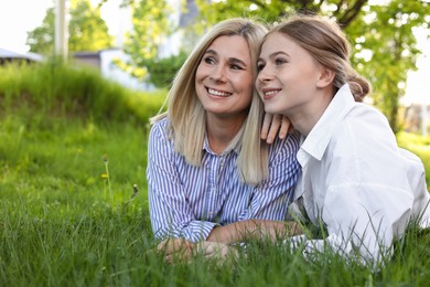 Happy mother with her daughter on green grass in park