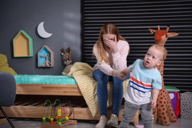 Depressed single mother with baby in children's room