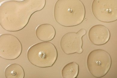 Drops of hydrophilic oil on beige background, flat lay