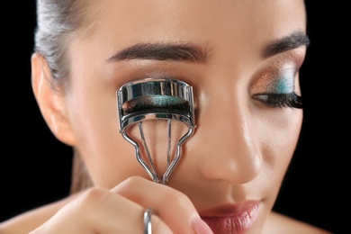 Young woman curling her eyelash extensions, closeup