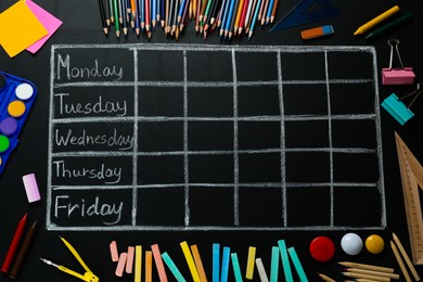 Many different stationery and drawn weekly school timetable on black chalkboard, flat lay