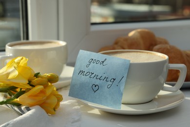 Coffee, flowers and card with phrase GOOD MORNING! near window