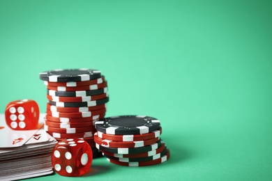 Poker chips, cards and dices on green background, space for text