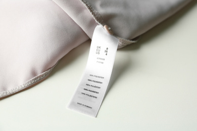 Clothing label with size and content information on light garment, closeup